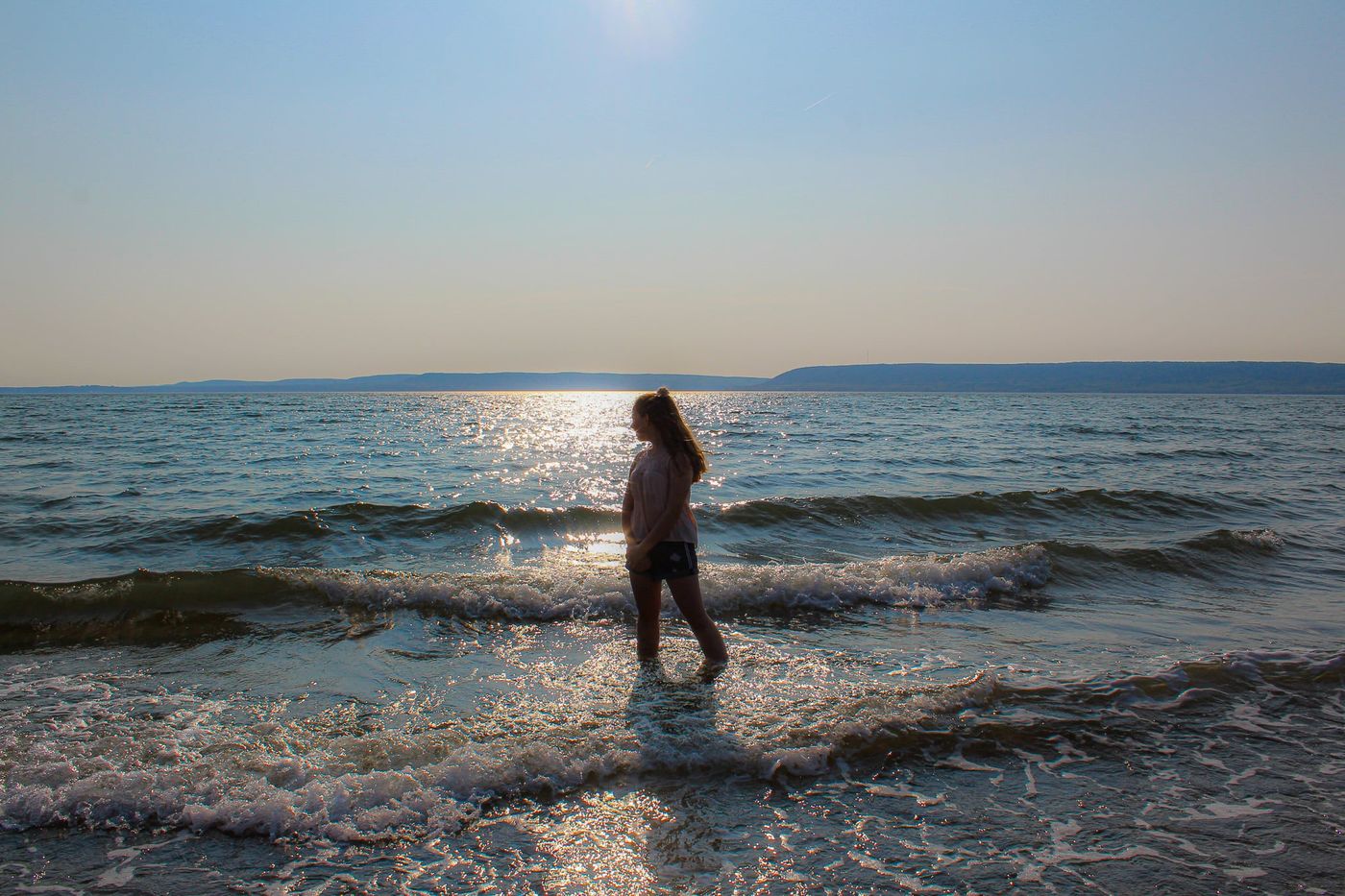 Girl wading into sparkling waves at sunset