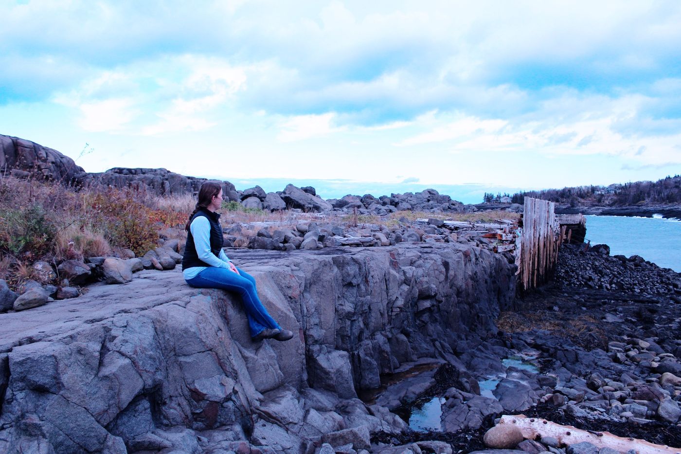 Woman sitting on coastal rocks looking out to sea
