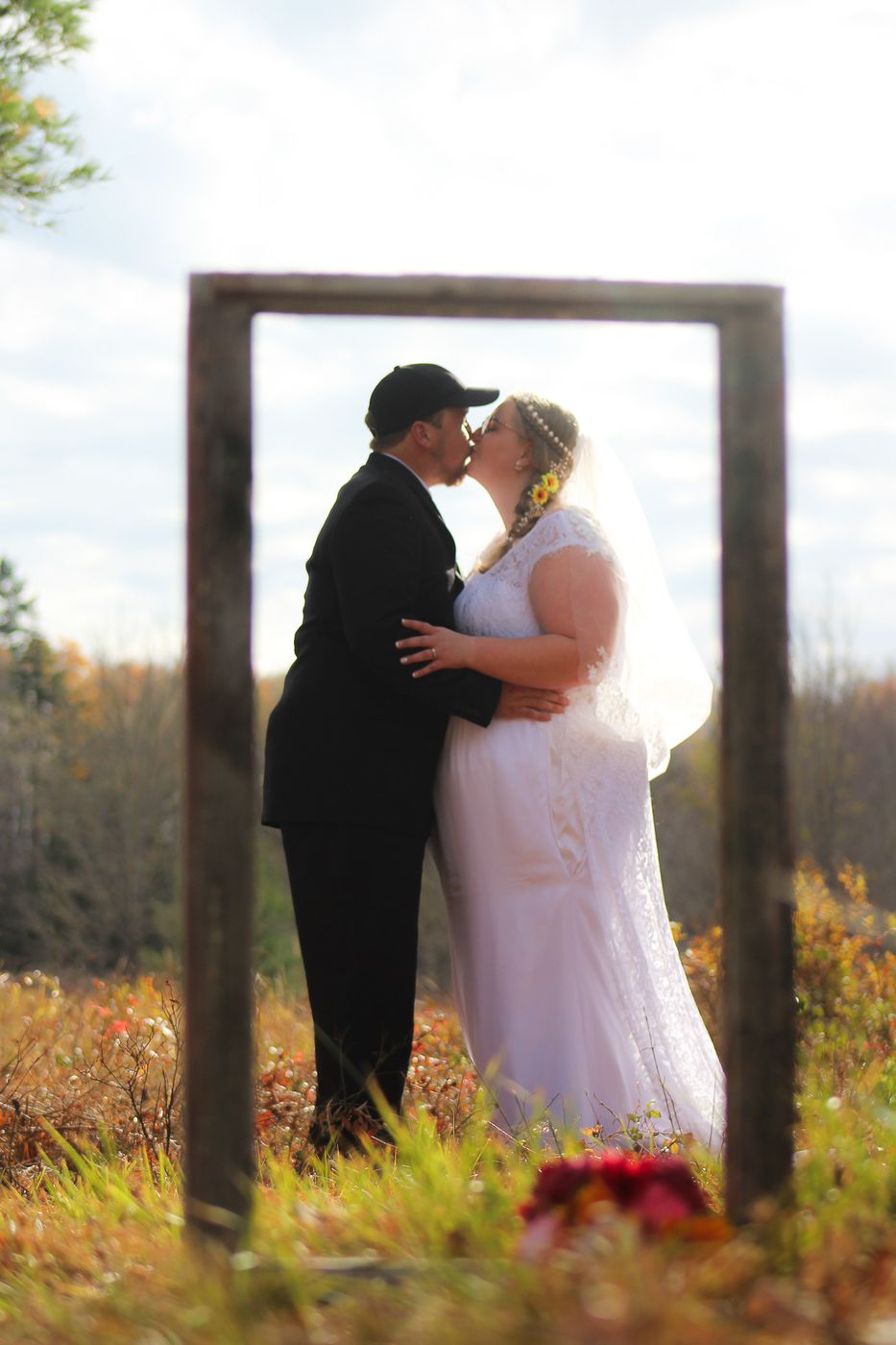 Bride and groom kissing inside a rustic wooden frame